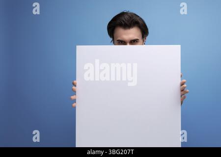 Young brutal brunette guy with poster mockup Stock Photo