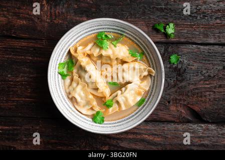 Wonton soup bowl. Shrimp or pork wonton soup with ciliantro, top view. Asian style lunch - dumpling soup. Stock Photo