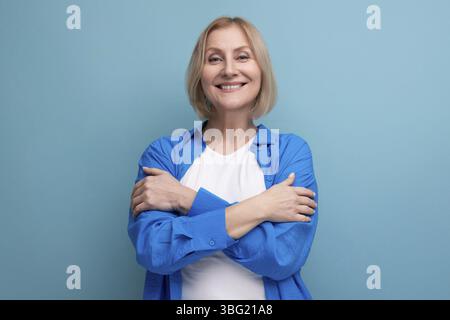 Energetic 50s woman in an attractive look on a blue background with copy space Stock Photo