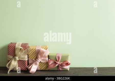 Colorful gift boxes on wooden table. green wall background Stock Photo