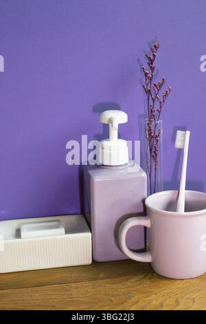 Bathroom accessories hygiene objects on wooden table. purple wall background Stock Photo