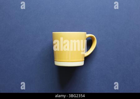 Yellow mug cup on blue background. top view, copy space Stock Photo