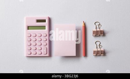 Pink digital calculator, memo pad, pencil, clip on purple background. top view, copy space Stock Photo