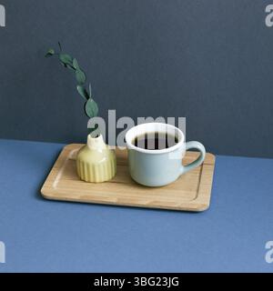Cup of coffee and eucalyptus leaf on table. navy blue wall background Stock Photo