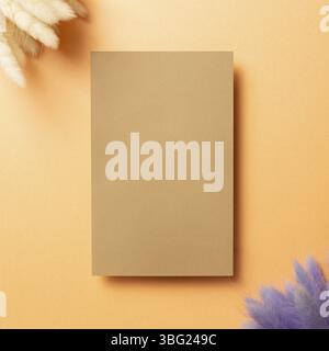 Blank empty paper with colorful hares tail grass (Lagurus ovatus) dry flowers on orange background. top view, copy space Stock Photo