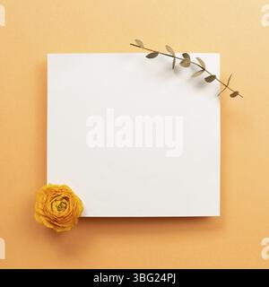 Blank memo pad with dry flower on orange background. top view, copy space Stock Photo