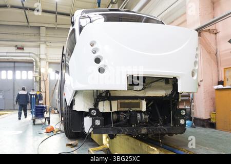 One working day of modern automatic bus manufacturing with unfinished cars workers in protective uniform automobile production Stock Photo