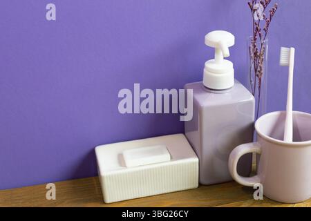 Bathroom accessories hygiene objects on wooden table. purple wall background Stock Photo
