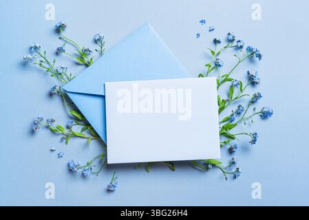 Greeting or invitation card mockup and envelope design, empty blank card and floral decor on blue background, copy space. Creative mockup with wild de Stock Photo