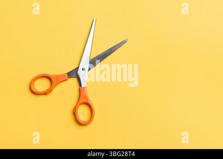 Open scissors on bright yellow background, top view, copy space. Stock Photo