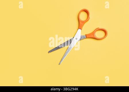 Open scissors on bright yellow background, top view, copy space. Stock Photo