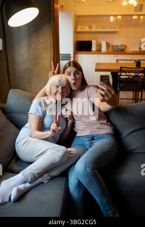 Young female volunteer and elderly woman making selfie and looking enjoyed Stock Photo