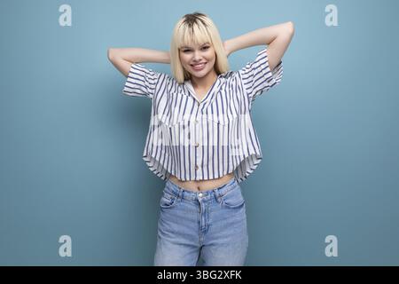 Positive energetic blond young lady in casual outfit with smartphone in studio Stock Photo