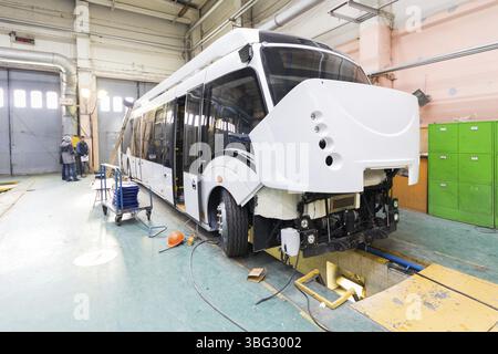 One working day of modern automatic bus manufacturing with unfinished cars workers in protective uniform automobile production Stock Photo