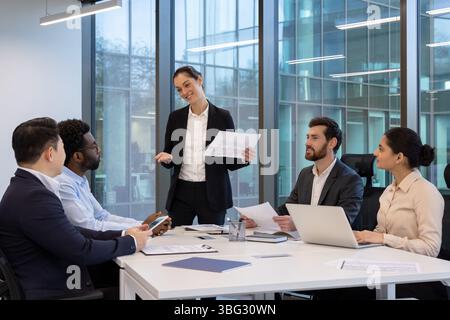 A diverse business team engages in a collaborative discussion during a meeting in a modern office environment. Stock Photo