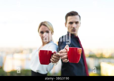 Couple of caucasian businessmen, young attractive brunette man in dark suit, red tie and black shirt, and pretty blonde woman in white blouse and blac Stock Photo