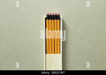 Yellow pencils in wooden pencil case on khaki background. top view, copy space Stock Photo