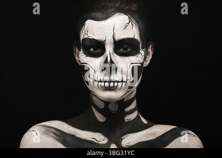 Isolated on black, closeup picture, beautiful young brunette caucasian woman with scull body art, grey eyes, serious Stock Photo