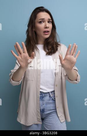 Confused brunette young brunette lady dressed in shirt and jeans Stock Photo