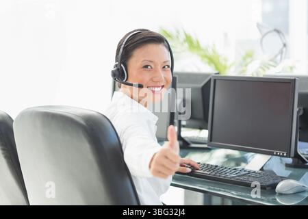 Headset resting on black leather chair at glass desk with monitors keyboard mouse in bright office Stock Photo