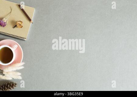 Notebook and cup of black tea with dry plant on gray background. top view, copy space Stock Photo