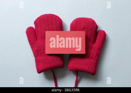 Blank card and winter red knitted gloves on gray background. top view, copy space Stock Photo