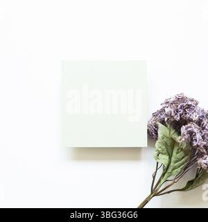 Blank green memo pad with purple hydrangea flower bouquet on white background. top view, copy space Stock Photo