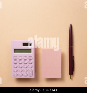Work and study place, memo pad and digital calculator and pen on beige pink background. flat lay, top view, copy space Stock Photo