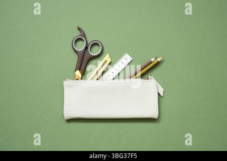 School office writing supplies in pencil case on green desk. top view, copy space Stock Photo