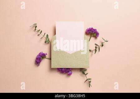 Kraft envelope and empty card with statice flower, eucalyptus leaves on pink background. Floral composition, flat lay, top view, copy space Stock Photo