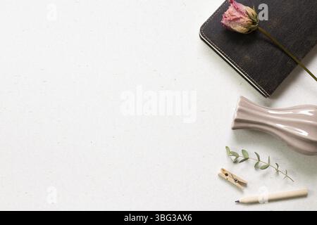 Notebook and pencil with dry flower on white background. flat lay, top view, copy space. Work and study place Stock Photo