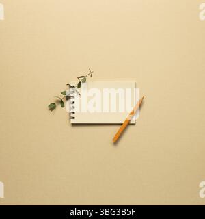 Empty kraft notepad with colored pencil on beige background. top view, copy space Stock Photo