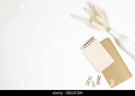 Notebook with vase of dry grass on white background. flat lay, top view, copy space. Work and study place Stock Photo