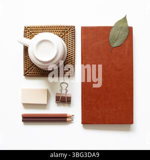 Office desk. Notebook, colored pencel, clip, eraser, cup on white background. top view, copy space Stock Photo
