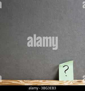 Sticky memo note paper with question mark on the gray wall. Thinking, solution, business, idea concept Stock Photo