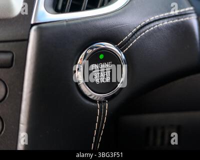 This image highlights a sleek engine start/stop button inside a modern vehicle, typically located on the dashboard, offering keyless ignition function Stock Photo