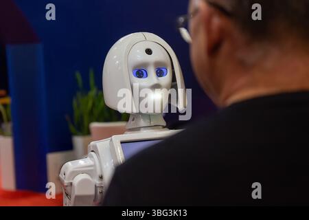 A man communicates from a humanoid robot assistant. Technology Stock Photo