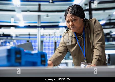 Female plant consultant examines production insight on laptop, ensuring efficiency and professionalism in the solar power facility. Working on renewable energy success for industrial operations. Stock Photo