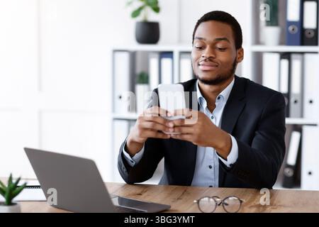 Young african man in suit using smartphone in office Stock Photo