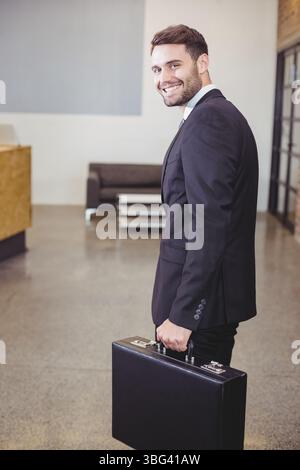Black leather briefcase resting on polished concrete floor in office lobby with white coffee table Stock Photo