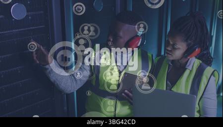 Image of falling icons over african american couple server room workers using headphones Stock Photo
