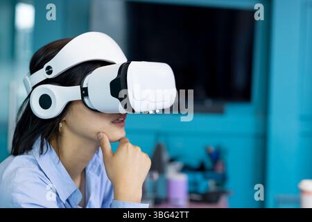 VR headset resting on desk in turquoise office, with pen cups, tech accessories and large monitor Stock Photo