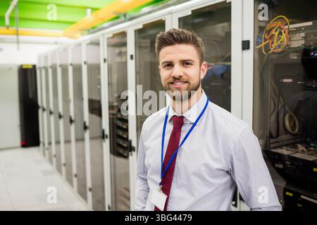 Male IT professional wearing light shirt, red tie inspecting server rack in data center, copy space Stock Photo