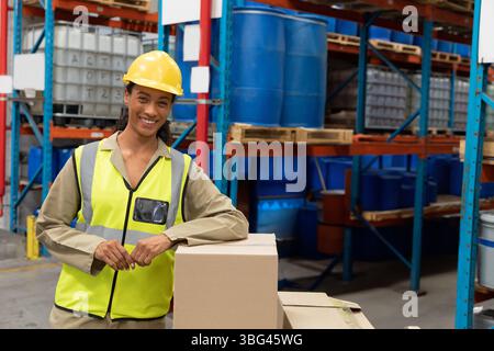 Blue plastic barrels are sitting on metal racks in warehouse with cardboard boxes in front Stock Photo
