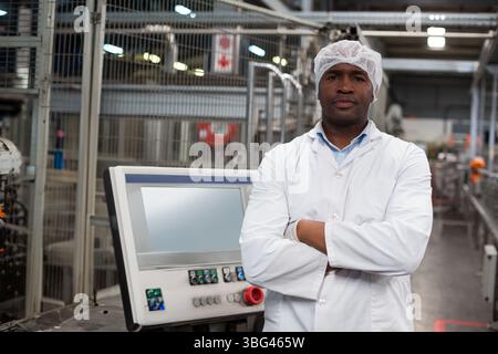 Mid adult African American man in lab coat inspecting touchscreen panel on plant floor, copy space Stock Photo
