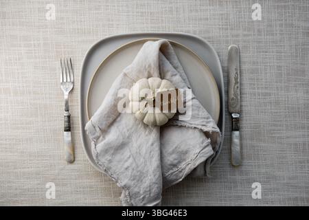 Plate setting decorated with white pumpkin, fall leaves and natural linen napkin for Thanksgiving dinner Stock Photo