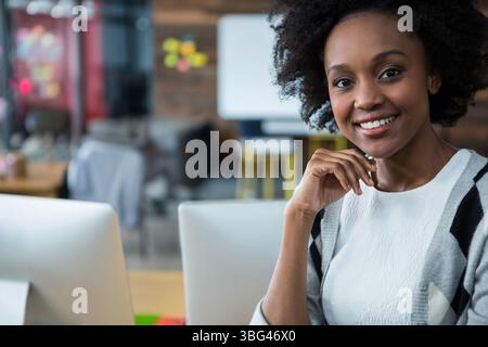 Two computer monitors glowing and keyboard resting on desk in office area with sticky notes Stock Photo