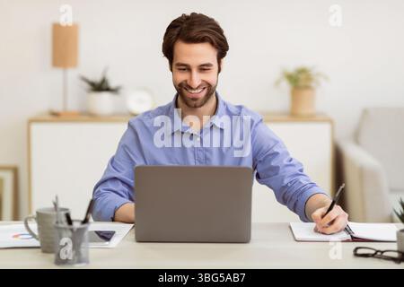 Business Guy Working Taking Notes Sitting At Laptop In Office Stock Photo