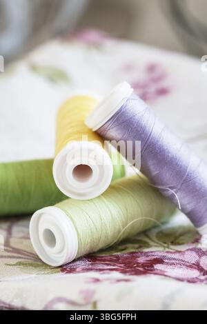 Colorful spools of thread on fabrics with floral patterns. Graphic resources Stock Photo
