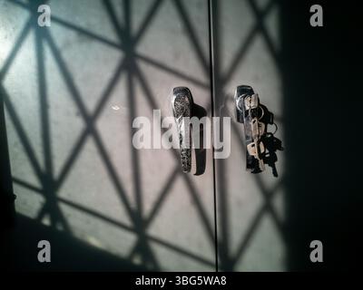 A striking image capturing shadows cast by light on a metallic door, featuring a key and handle, evoking a sense of mystery and security in an indoor Stock Photo